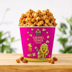 Caramel Crunch De Home Mart popcorn cup on a wooden table