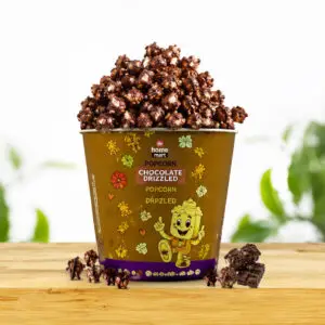Chocolate drizzled De Home Mart popcorn cup on a wooden table